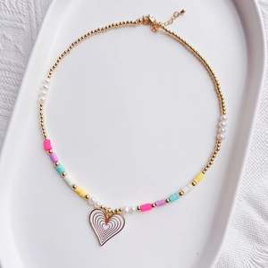 Detail view of a handmade bohemian beaded heart necklace on a white ceramic tray