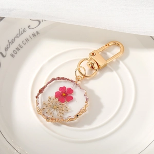 Detail of handmade resin keychain featuring dried flowers and gold foil accents