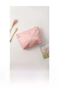 Detail of pink textured makeup bag fabric with H&R label and cosmetic brushes