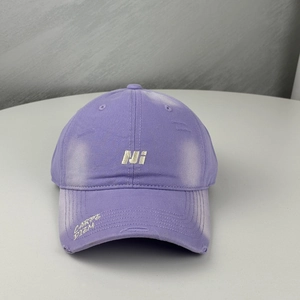 Detailed close-up of purple cotton baseball cap with silver embroidery and distressed holes