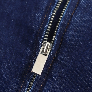 Détail de la fermeture éclair métallique sur une robe midi en denim bleu foncé sans manches