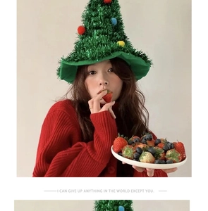 Detail of green sparkly Christmas tree hat with colorful pom-poms and festive tinsel