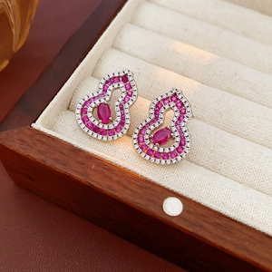 Close-up of gourd earrings with pink oval stones in a premium jewelry display box