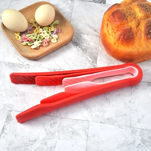 Three-piece red kitchen food tongs set for bread and salad on marble tabletop