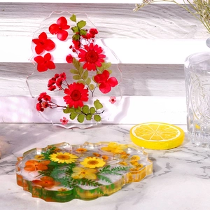 Macro view of irregular resin coasters with red and yellow dried flowers and wavy edges