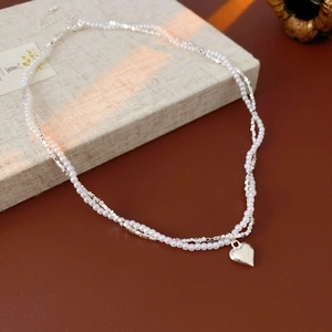 Detailed close-up of a double-layered pearl necklace with a silver heart-shaped pendant