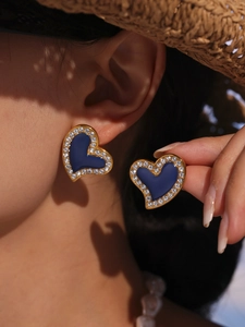 Macro detail of royal blue heart earrings with 18K gold plating and sparkling zircons