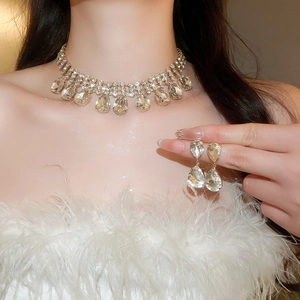 Close-up of elegant gold tassel necklace and teardrop crystal earrings set on a model