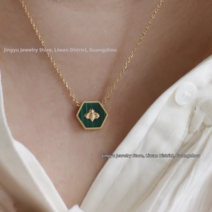 Detail of a vintage gold honeycomb necklace with green enamel and a golden bee pendant