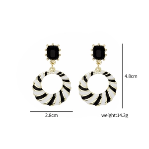 Detailed view of geometric black and white enamel earrings with size and weight metrics