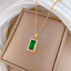 Close-up of green emerald pendant with crystal halo on gold chain necklace