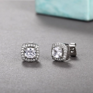 Detail view of cushion cut halo stud earrings with sparkling cubic zirconia on dark background
