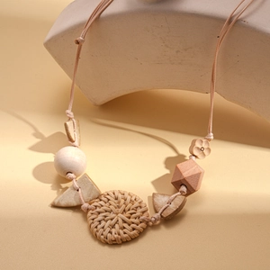 Bohemian sweater necklace with wooden beads and woven rattan pendant on stone props