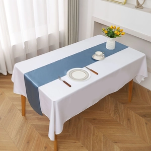 Blue satin table runner on a white tablecloth with yellow tulips for wedding decor