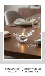 Detail of bird shaped clear glass candle holder with a glowing tea light on a warm dinner table