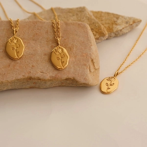 Detailed view of three vintage gold rose necklaces on natural stones with warm lighting