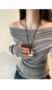 Dettaglio di una collana con ciondolo a borsa argentata su un lungo cordino nero
