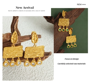 Detail of vintage gold textured rectangular earrings with dangling zircon accents