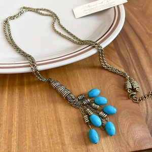 Detailed shot of bohemian turquoise beaded tassel on gold-tone vintage twisted chain