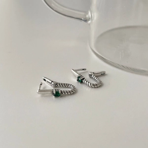 Macro detail of S925 sterling silver hoop earrings with emerald green zircon stones