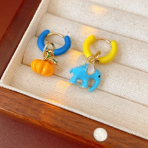Close-up of asymmetrical enamel elephant and pumpkin earrings in a wooden jewelry box