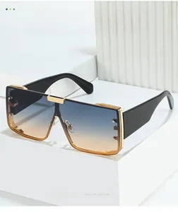 Detail of square sunglasses with blue to orange gradient lenses and gold-black frame