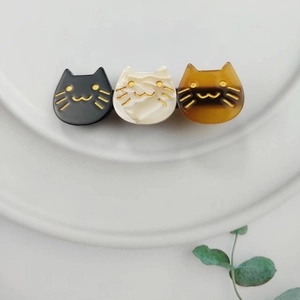 Detailed close-up of three acetate cat hair clips in black, cream, and tortoiseshell patterns