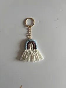 Detail of handmade bohemian rainbow keychain with blue and beige yarn and white fringe