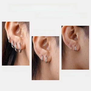 Detail showing multiple sizes of silver hoop earrings worn on ear with easy closure feature
