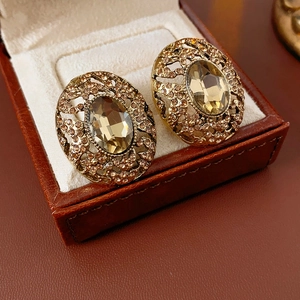 Close-up of vintage oval gold earrings with amber gemstones on brown leather display