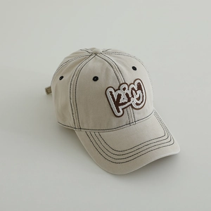 Detail of embroidered K&M patch on beige washed cotton baseball cap with contrast stitching