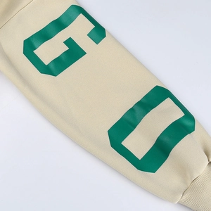 Détail de la manche d'un sweat crème avec imprimé lettres vertes et poignet en tricot
