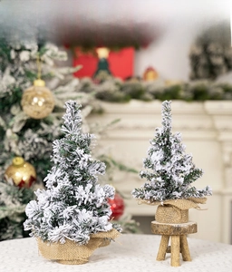 Detail of mini flocked snow Christmas trees with burlap bases in a cozy home setting