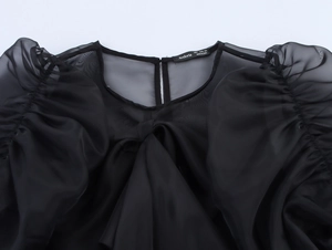 Détail du tissu en organza noir transparent avec manches bouffantes et étiquette S