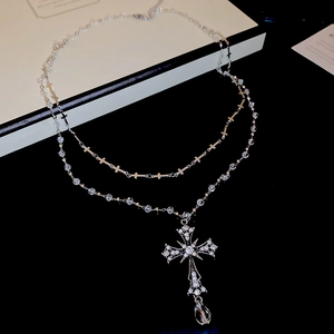 Dettaglio della collana argentata a due strati con ciondolo a croce e perline di cristallo