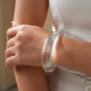 Close-up of a minimalist chunky transparent acrylic bangle on a woman's wrist