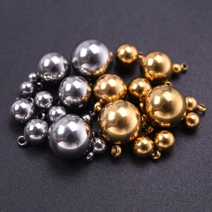Gros plan de divers pendentifs sphériques en acier inoxydable or et argent en tailles assorties