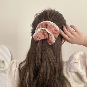 Detailed back view of pink floral scrunchie with white lace trim on long hair