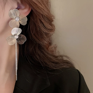 Détail de boucles d'oreilles fleur argentée à pampilles avec zircons sur un mannequin