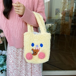 Detail of yellow plush handbag featuring cute embroidered bear and soft fleece texture