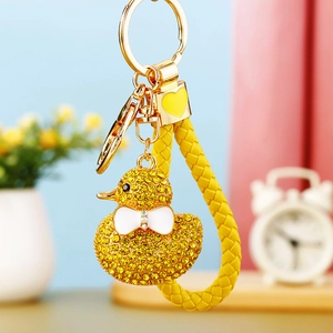 Close-up of a sparkling rhinestone duck keychain with gold hardware and a yellow woven strap
