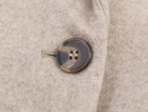 Macro view of the single marbled button and premium wool texture on oatmeal blazer