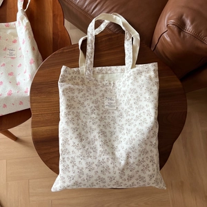 Flat lay of cream canvas tote bag with brown floral patterns on a wooden table