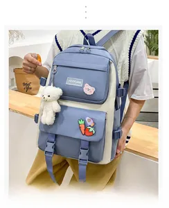 Detail of blue and white canvas backpack with plush bear charm and cartoon patches