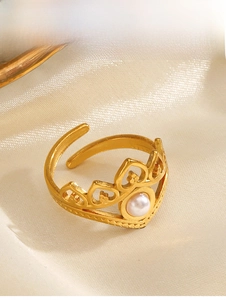 Detailed view of a crown-shaped gold ring with pearl inlay on a silk background