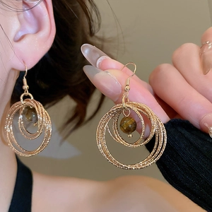 Detailed close-up of gold layered hoop earrings featuring centered tiger eye stone beads