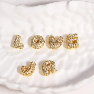 Détail de pendentifs lettres dorées L O V E J R avec zircons dans une coupelle en céramique