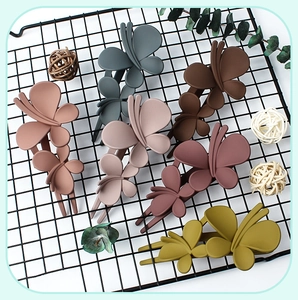 Collection of large matte butterfly hair clips in various muted colors on a black grid