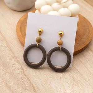 Retro geometric hollow wood hoop earrings with gold metal studs on a wooden tray