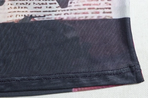 Detail of sheer mesh fabric with newspaper print and double-stitched hem on a black skirt